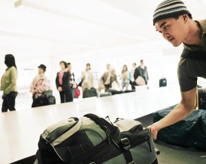 Travellers standing by airport carousel, young man picking luggage